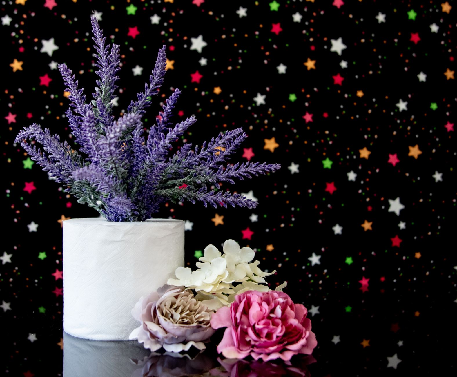 Creative floral arrangement in a toilet paper roll with starry backdrop, showcasing vibrant colors.